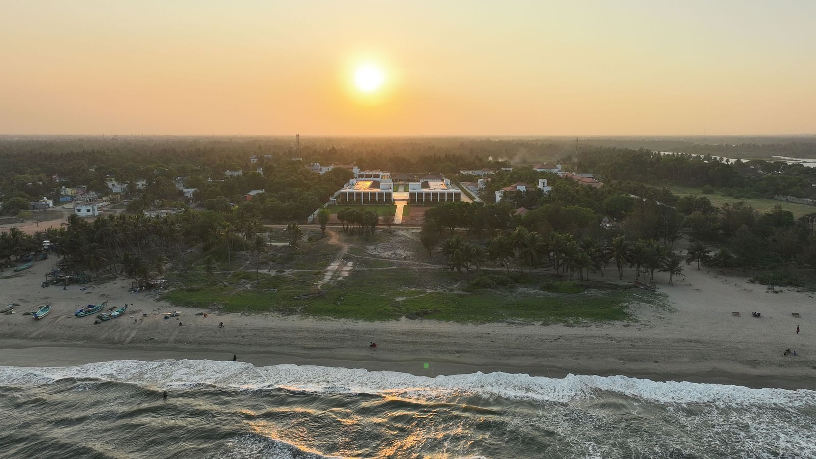 Facade image of the resort with the ocean waves crashing the beach shoreline at The Shore Trishvam, Pondicherry.