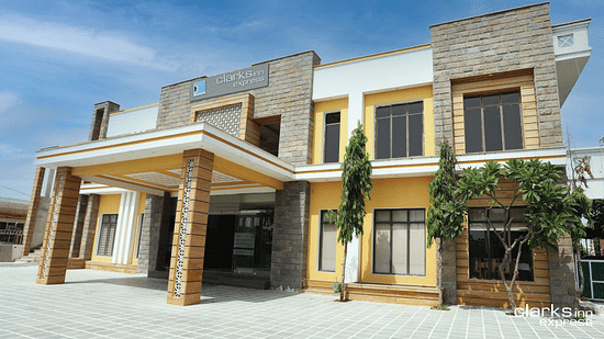 Facade of Clarks Inn Express, Bharatpur under clear sky with green creepers on the wall