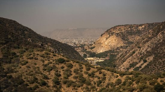 An overview of an arid hilly region with small shrubs seen.