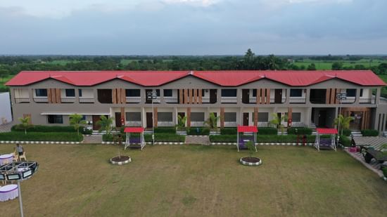 Wide drone view of VITS Select Diamond Resort, Sasan Gir showing two accommodation blocks facing the large green lawn.