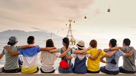 Friends sitting on a ledge near an ocean looking forward