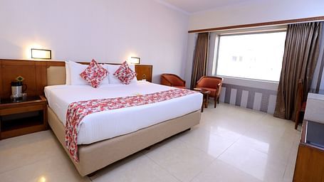 Executive room of Hotel Amar with a  bed table, TV, a big window and chairs