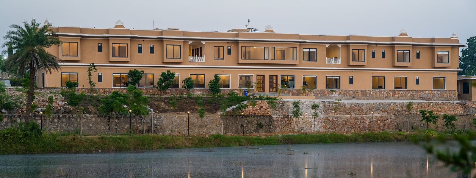 An evening view of a water body in front of a building in our wellness centre - Rajbagh Wellness, Udaipur