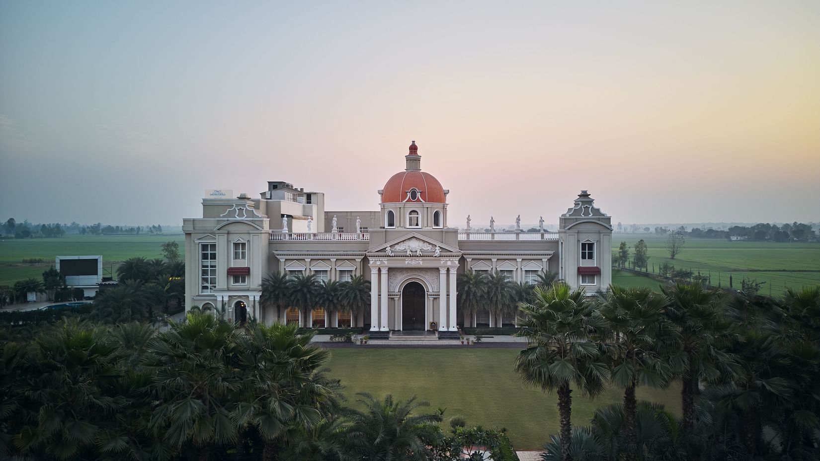 facade of Royal Kingdom Sarovar Portico, Pilibhit with trees in the foreground