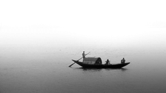 A small boat being ridden by a person with two other people on the boat in hooghly river