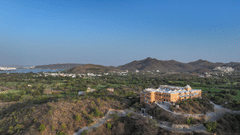 Aerial shot of Khas Mahal Suites, Udaipur surrounded by mountains and lush green landscapes.