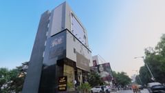 A facade image of Fortune House, Magarpatta surrounded by a few trees, and there is also a driveway in front of the building