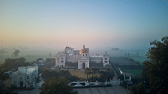facade of Royal Kingdom Sarovar Portico, Pilibhit with fog-covered fields in the distance