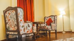 Two wooden sofa chairs with comfy cushions facing each other with a wooden teapoy in the middle, at the Super deluxe room at The Garden Ananta Elite.