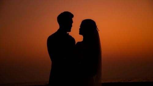 A silhouette of a couple looking at each other at sunset.