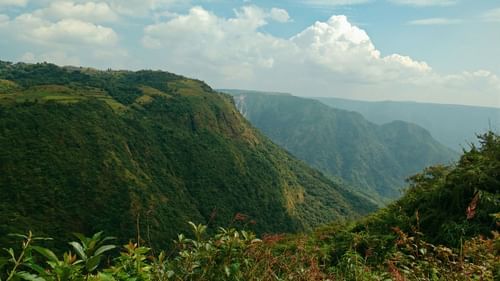 an overview of a viewpoint with a mountain in view and white clouds on blue sky in the background