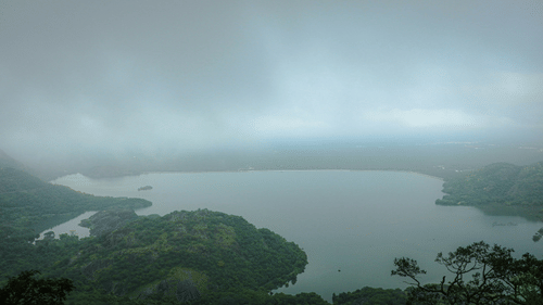An overview of a lake in Valparai with rains pouring down on the lake.