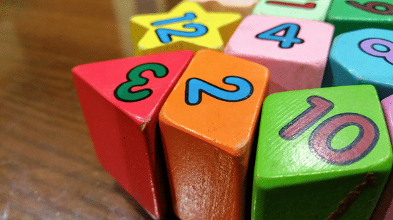 A close up of several wooden blocks of various colours with numbers written printed over it.