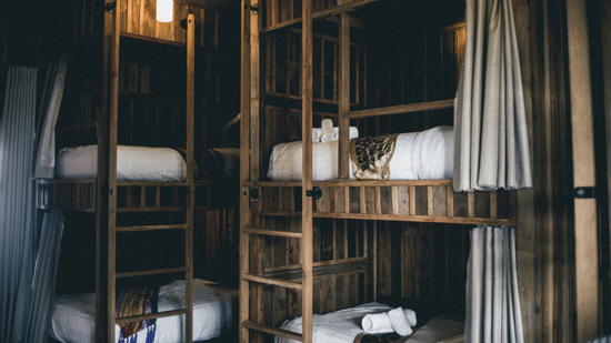Cosy interior of a hostel dorm room featuring dark wood bunk beds with white linens.