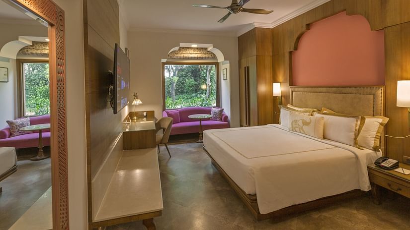 a double bed, side tables with lamps on it and a tv wall mounted opposite it inside premium room - Heritage Village Resorts & Spa, Manesar