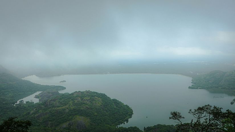 An overview of a lake in Valparai with rains pouring down on the lake