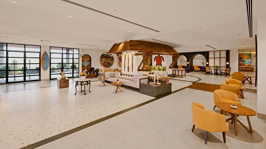 Lobby space with sofas and chairs, featuring wall hanging turtle craft, paddles, and candle holders at Cloud9 Sarovar Premiere, Palolem Goa