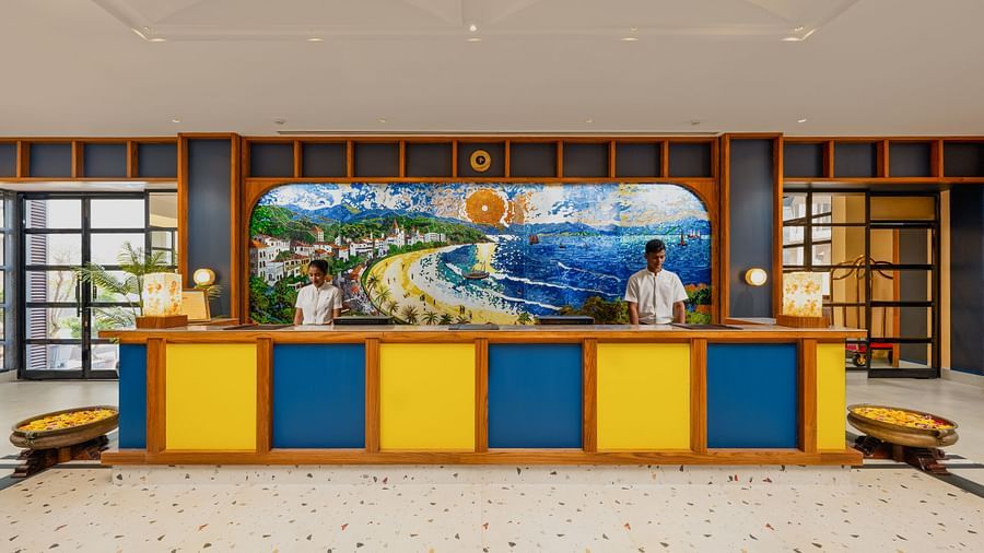 An image of a reception space with two individuals standing on each sides of the tables at Cloud9 Sarovar Premiere, Palolem Goa