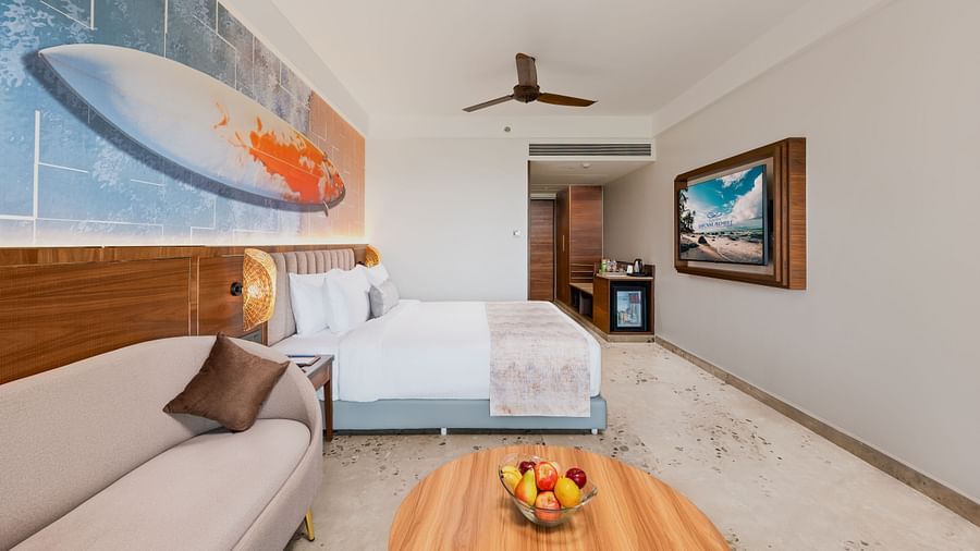 an image of a bedroom with surfboard painting and a wall mounted television at Cloud9 Sarovar Premiere, Palolem Goa
