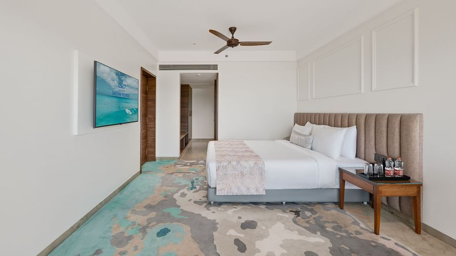 an image of side view of a bedroom with water bottles and glasses placed next to the bed at Cloud9 Sarovar Premiere, Palolem Goa.