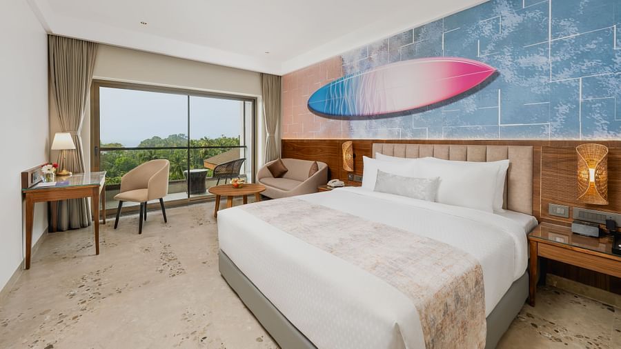 Bedroom with a basket of fruits, working table and chair, featuring a balcony with a view of greenery at Cloud9 Sarovar Premiere, Palolem Goa