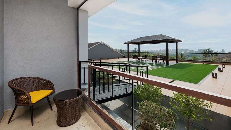 Balcony with a chair and table leading to the terrace at Cloud9 Sarovar Premiere, Palolem Goa