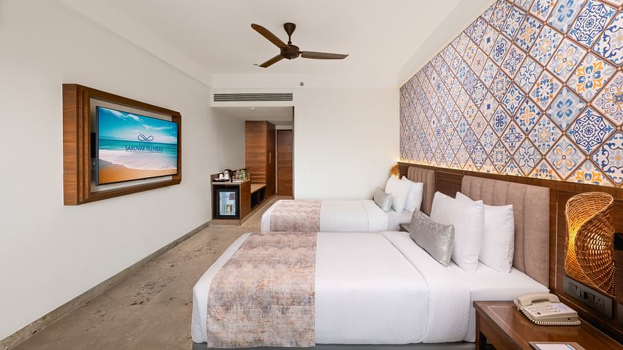 Side view of a bedroom featuring a patterned headboard and a wall-mounted television at Cloud9 Sarovar Premiere, Palolem Goa