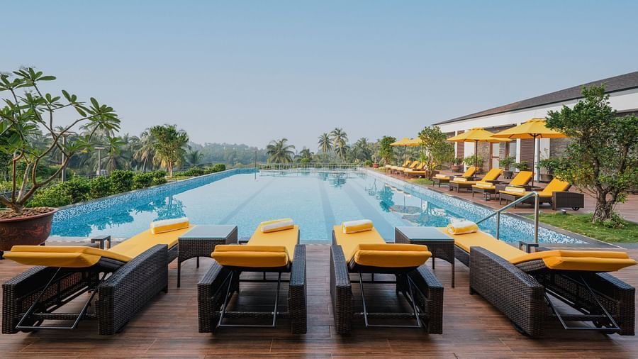 an image of crystal clear swimming pool surrounded by sun loungers at Cloud9 Sarovar Premiere, Palolem Goa