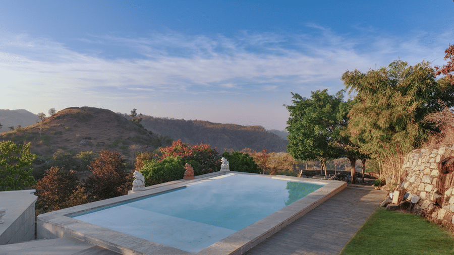 A swimming pool at Fateh Safari Resort, Kumbhalgarh  surrounded by trees and valleys.