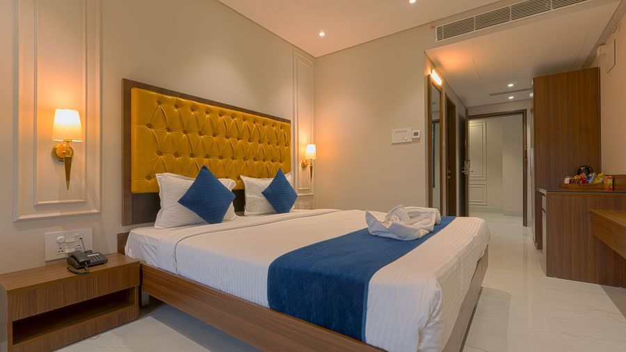 A double bed with cushioned headboard and side tables inside the deluxe suite - Magnus Nexstar Suites, Pune