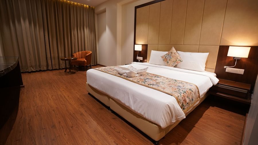 Standard Room With Swimming Pool Or City View at Pride Hotel Bhopal featuring a plush bed with lamps on both sides lit up over the nightstands and a sitting area in the background with a couch and a coffee table