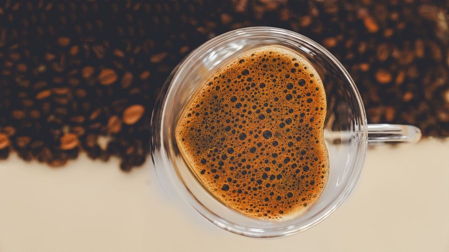 An image of  a cup of coffee and on one side coffee beans are placed - The Garden Ananta Elite, Rajkot