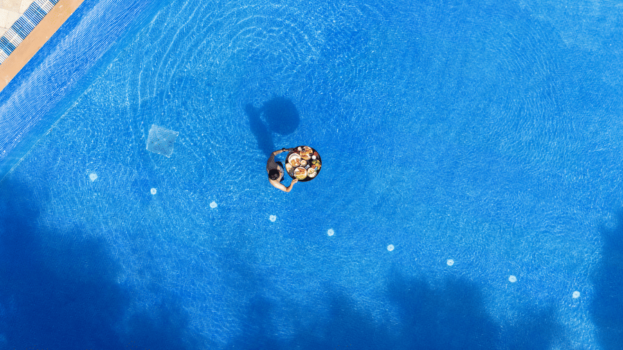 person floating  near the floating tray holding breakfast items and drinks in a blue swimming pool at The Golden Tusk, Jim Corbett