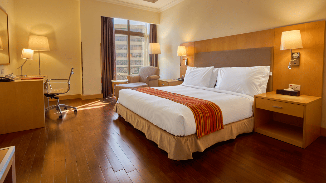 Bedroom interior with king bed, bedside lamps, wooden furniture, and modern decor in cosy atmosphere  - Ramada by Wyndham Addis