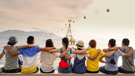 A group of friend sitting with arms around each other and looking at the landscape in front of them, symbolising team building activities in Goa