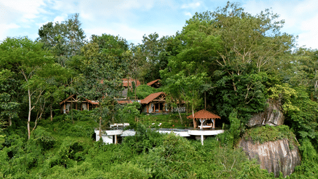 Hillside at Estate Aana Pana with stone and timber buildings, a curving terrace with an infinity-edge pool and a pavilion at Earthitects Holiday Experiences.