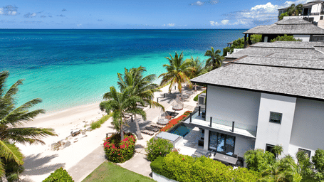 The exterior view of a villa at Tamarind Hills Resort and Villas - Antigua, overlooking clear waters and lush greenery.
