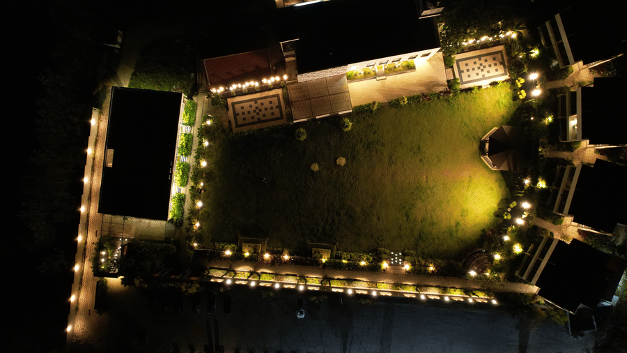 Dramatic aerial night-time view of a large outdoor venue or sports field surrounded by numerous perimeter lights and floodlights at Bindiga Peak Resorts.