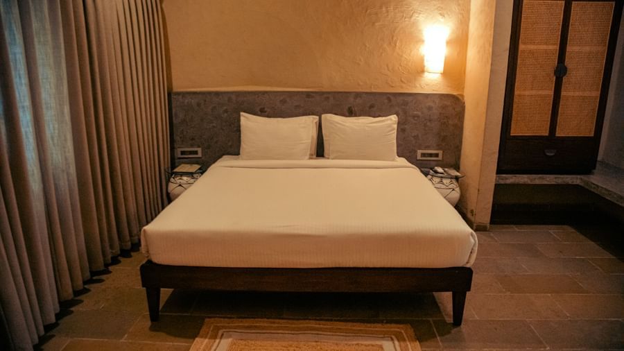 Bedroom with a king size bed, tall curtains, a wardrobe and wall-mounted lights at Fireflies Resorts, Kabini.