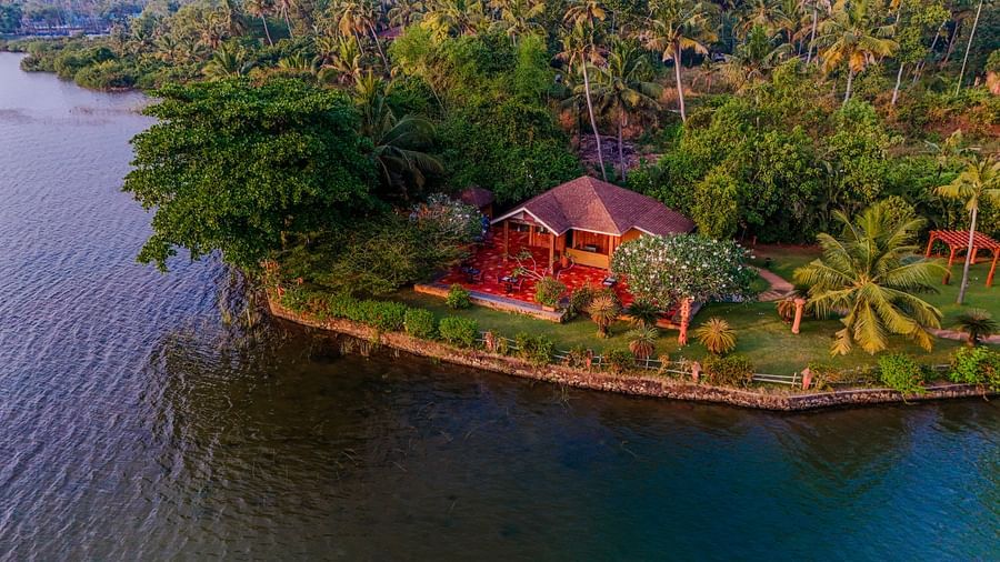 Aerial view of a resort with villas on a riverbank with a view of the water.