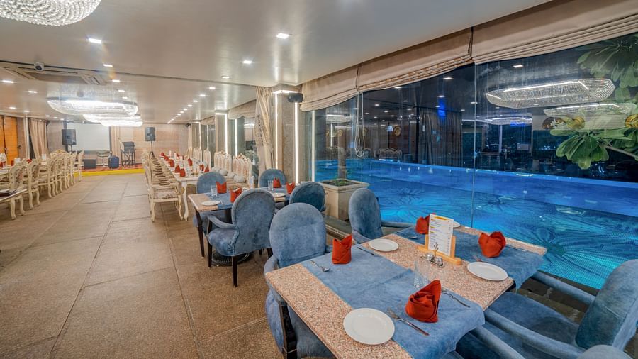 An indoor dining setup next to a pool at Hotel Ashok Nagpur. 