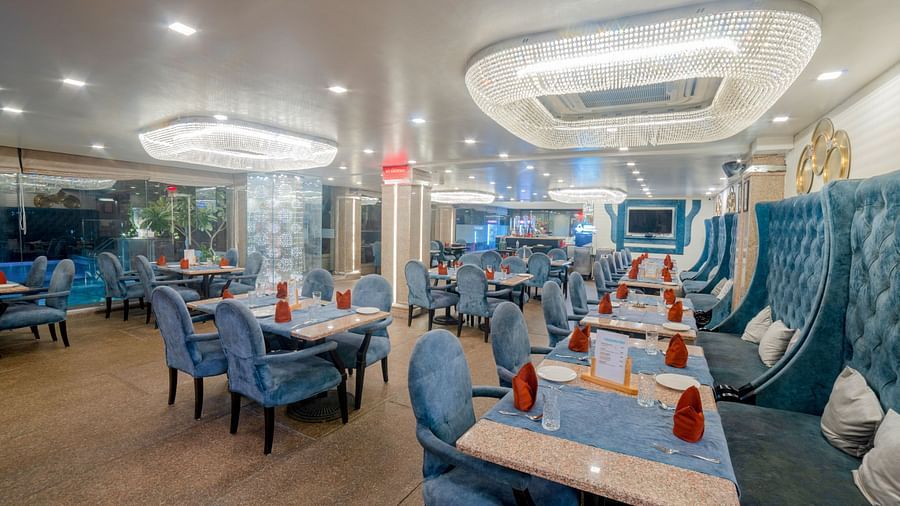 An indoor dining setup at Hotel Ashok Nagpur with cushioned chairs around tables