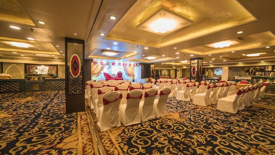 Maurya featuring rows of chairs facing a stage with patterned flooring and ambient lightning.