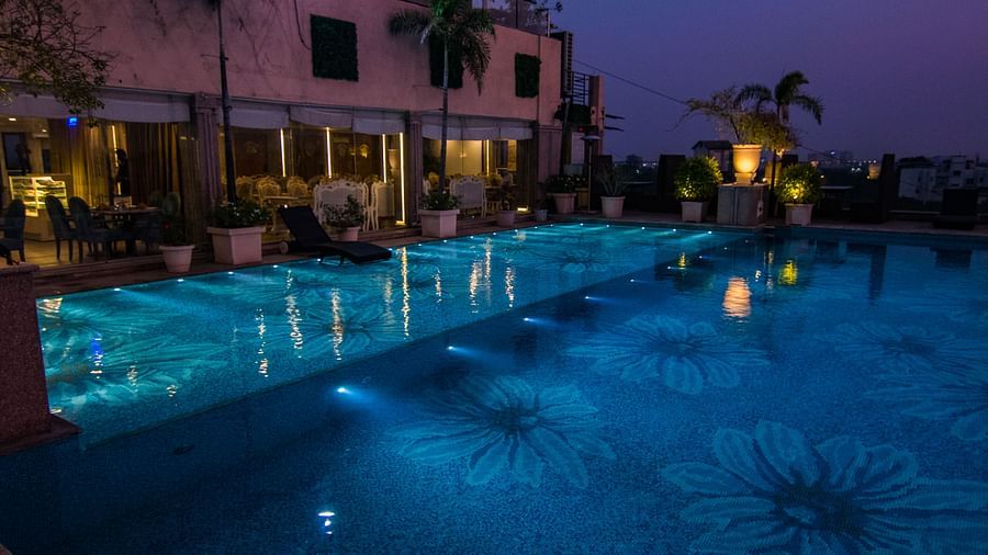 View of the swimming pool at night surrounded by lights at Hotel Ashok Nagpur.