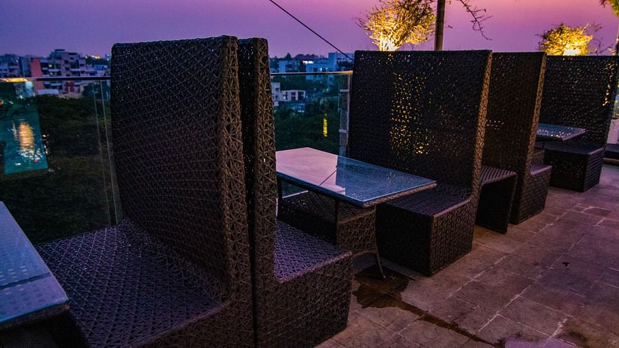A dimly lit outdoor seating area with dark furniture and a small table at Hotel Ashok Nagpur.