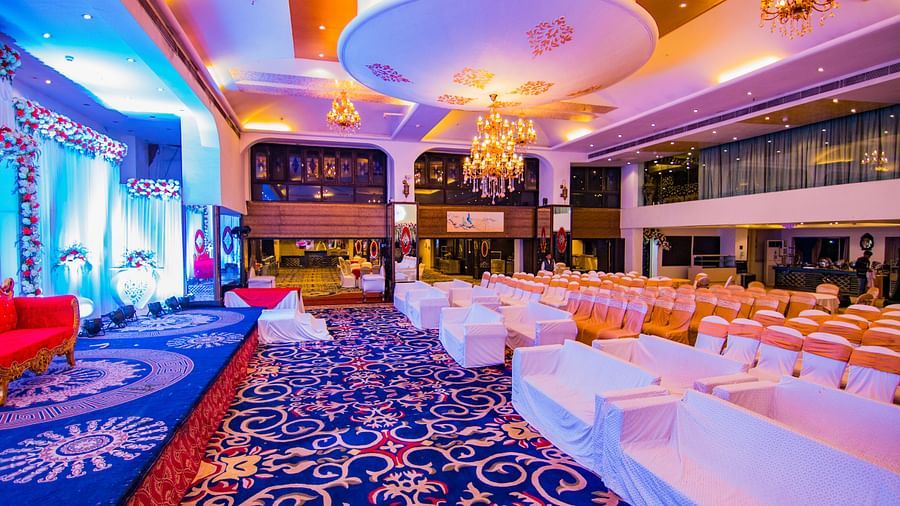Kohinoor highlighting the table and chair setup, blue carpet patterns, and overall event space design.