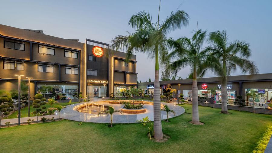 Facade and well-manicured lawn of Hotel Highway King, Behror, which also features a large illuminated logo of the property.
