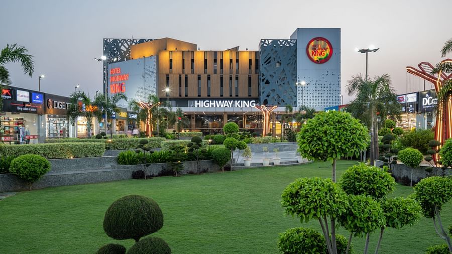 Wide-angle exterior shot of Hotel Highway King, Bilaspur, with lush landscaping and night lighting.