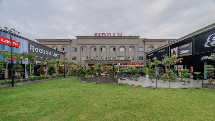 Green lawn and landscaped front yard outside Highway King Dhodsar.