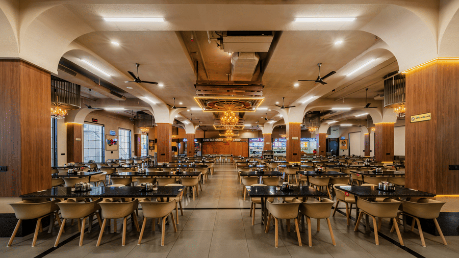 A grand restaurant layout displaying orderly dining tables, seating arrangements, and detailed ceiling work at Hotel Highway King, Harmada.